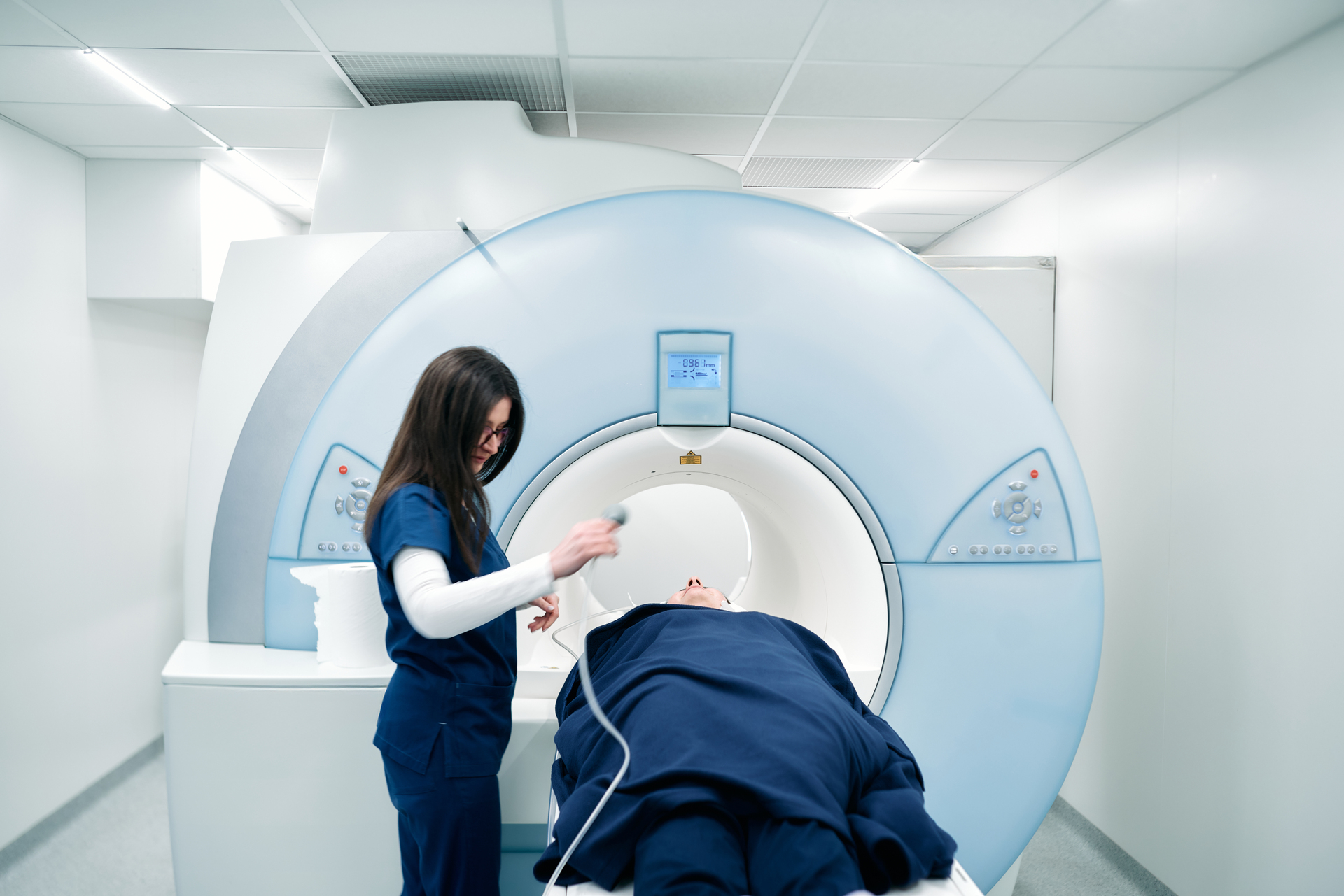 A nurse or medical technician prepares a patient for an MRI scan or MRI scanner